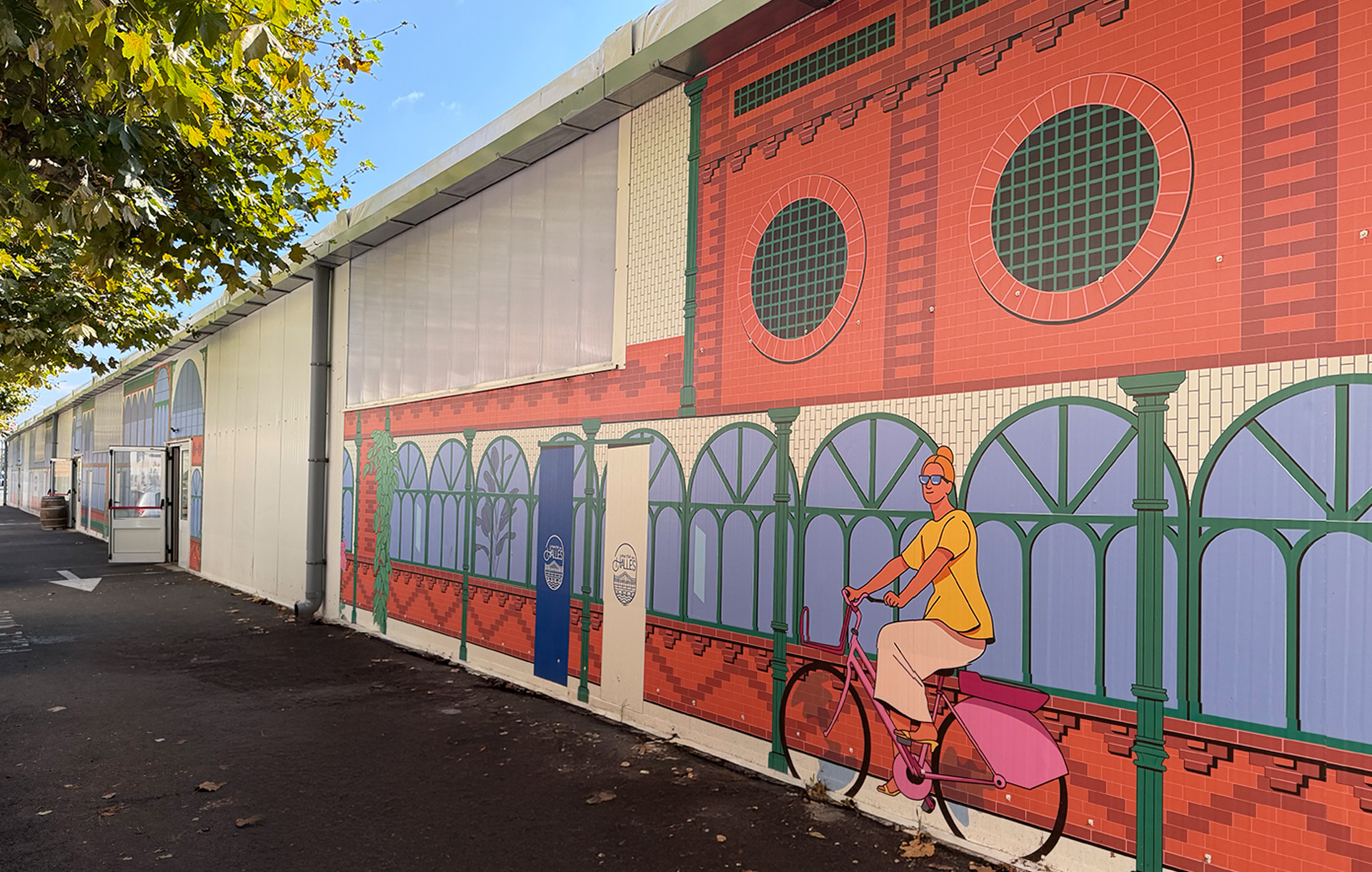 Longue façade du marché entièrement recouverte par l'illustration graphique.